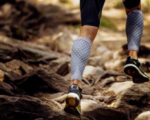 Jambes d'une personne qui fait un trail en portant des manchons de compression