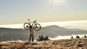 Homme qui porte son vélo en pleine montagne